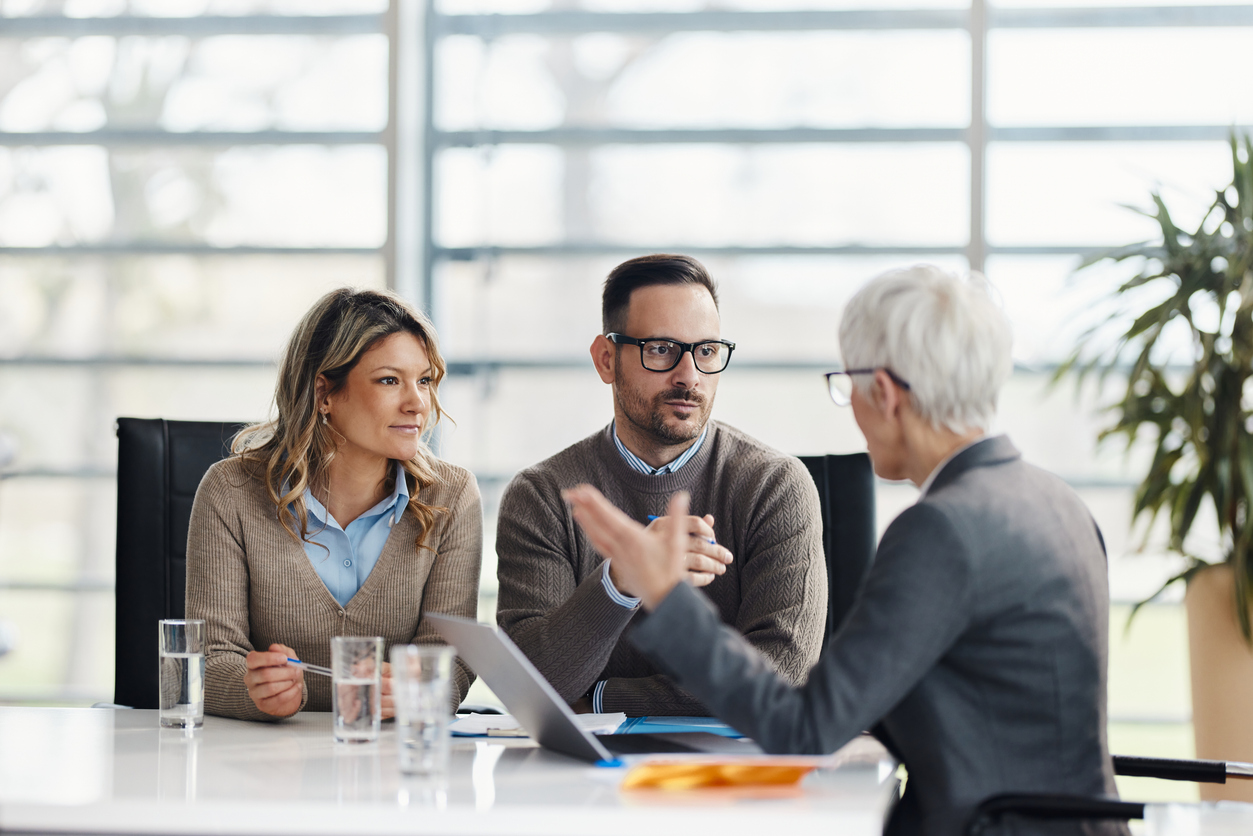 Insurance adviser explaining IUL policy backdating and age nearest premium savings to a couple in a meeting